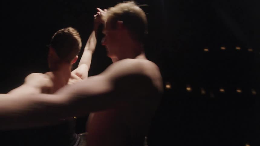 Two dancers perform a ballet lift on stage exuding elegance with outstretched arms and poised balance