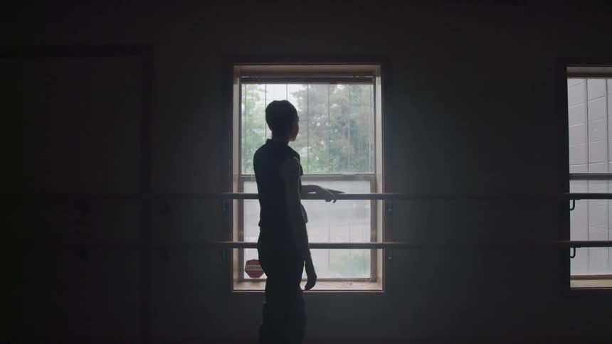 A woman is looking out the window in the ballet studio