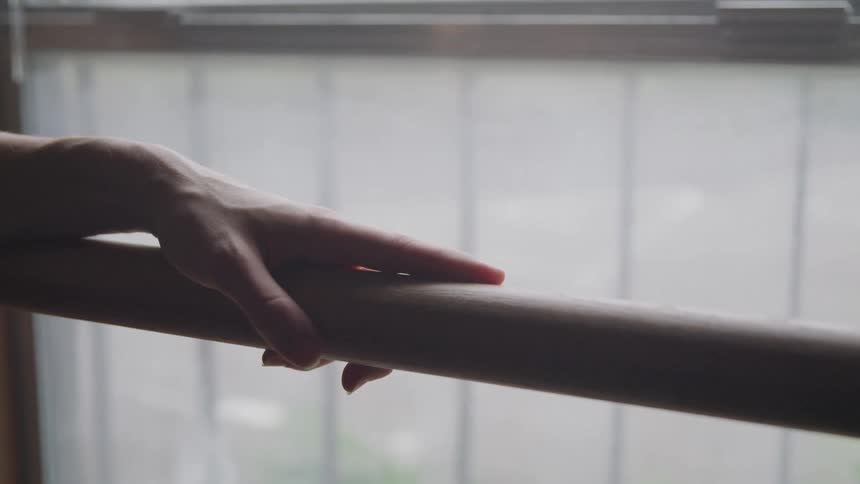 A ballet dancer is touching the ballet barre