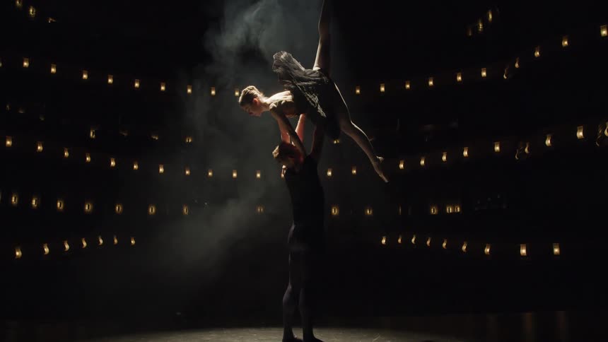 Two ballet dancers perform under a spotlight
