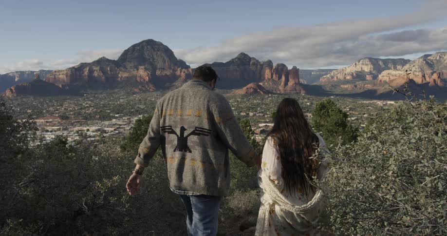 A man and woman hand hands as they hike downhill