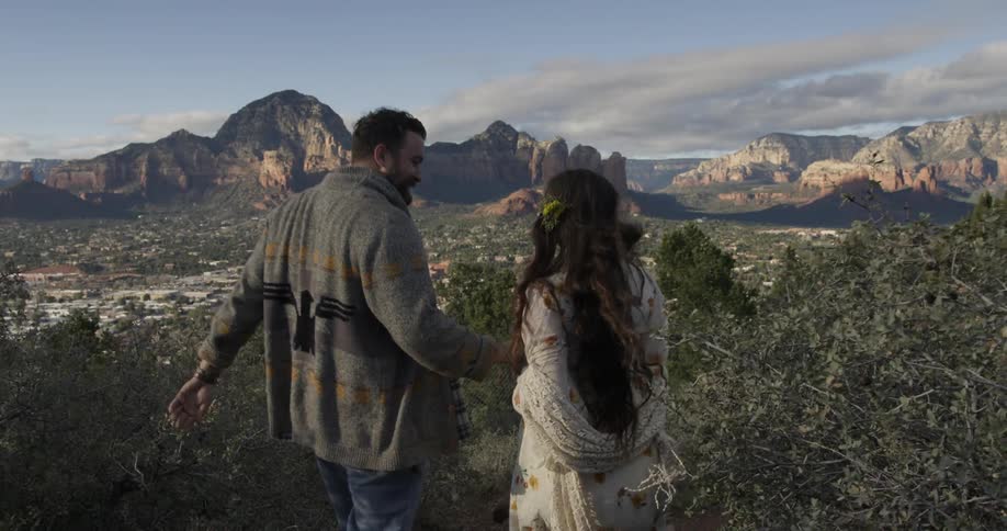 Man and woman hold hands as they walk through nature