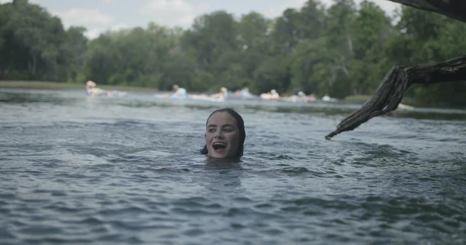 A girl in a lake swimming and smiling