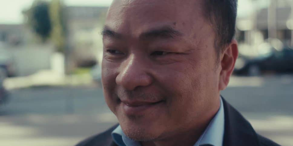 Man with a happy facial expression standing outdoors holding a pen and tablet