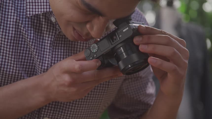A young man is taking photographs using his camera on a summer day