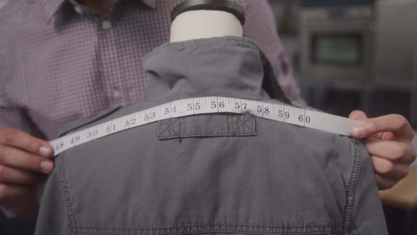 A man is using a tape measure on a shirt