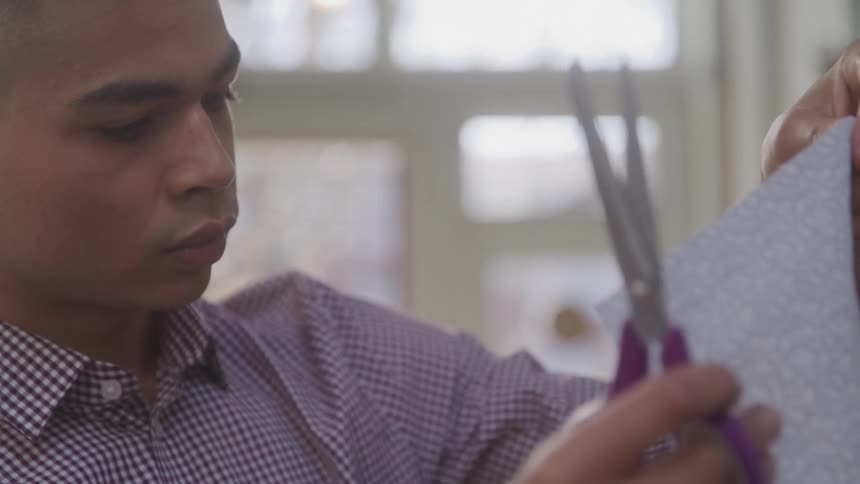 A tailor is holding scissors and a piece of fabric