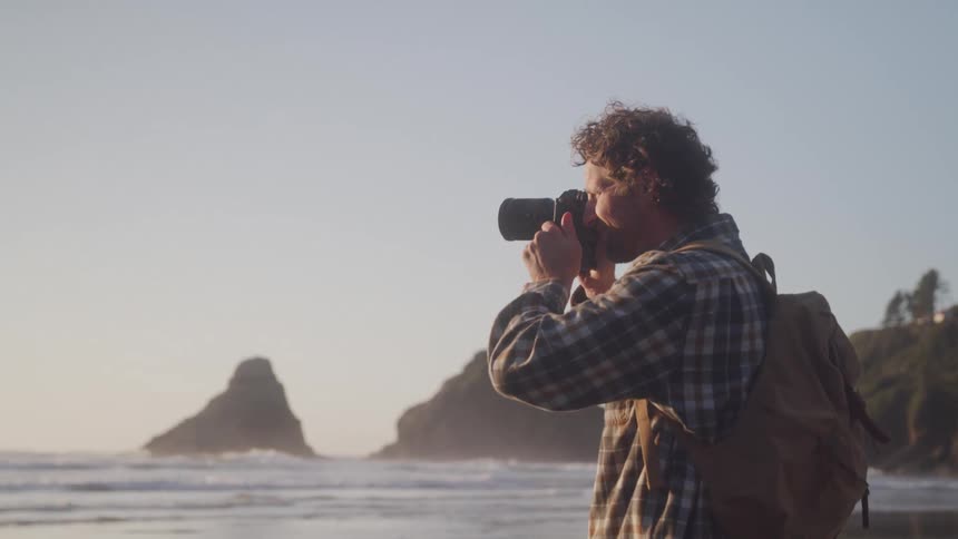 Photographer taking pictures while standing on a deserted beach at sunrise