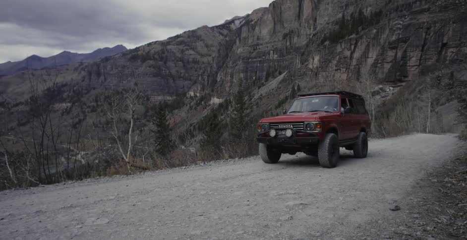 Truck driving on dirt road surrounded by mountains