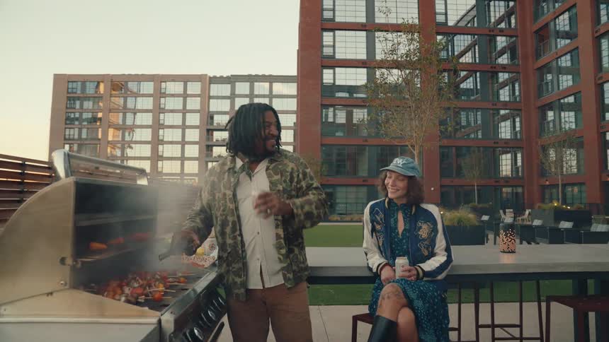 Man drinking beer and having barbecue while talking to a woman next to him