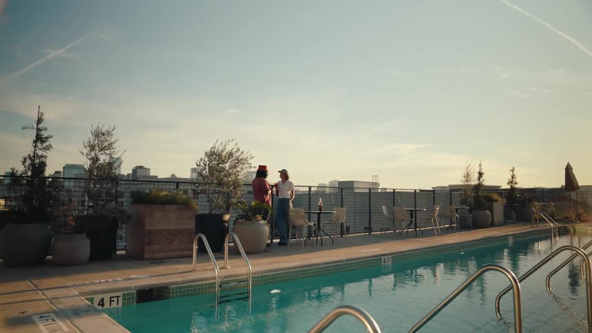 Woman and a man talking on the terrace of a building by the pool