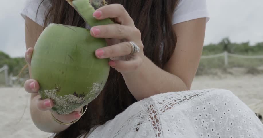 Long-haired woman enjoying a beverage while sitting at the beach