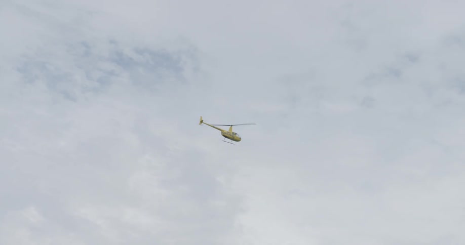 A helicopter is flying in a cloudy sky