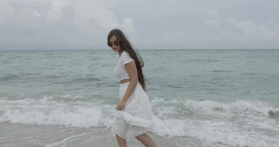 Woman in white skirt walking in shallow ocean waves
