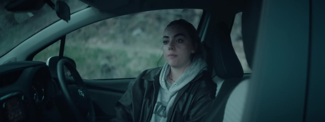 A woman puts her hands on her head as she sits in a car