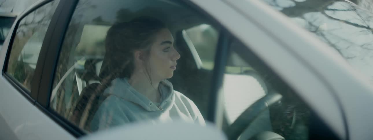 A woman looks around as she sits in a car