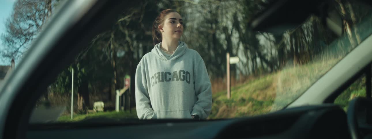A woman is standing and pacing outside of a vehicle