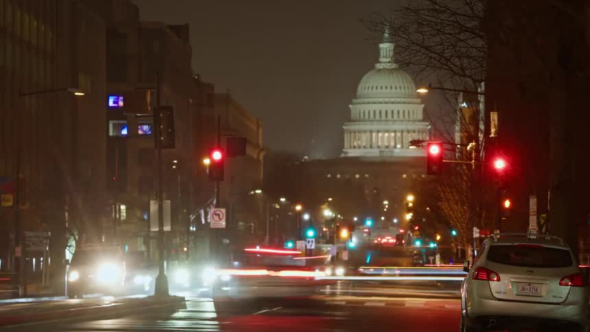 Empty street at night with the united states capitol in the background and illuminated traffic signals