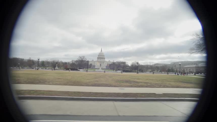 A park in front of a landmark is revealed while moving down the street