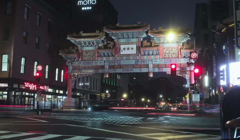 Pedestrians and cars travel through the intersection at night