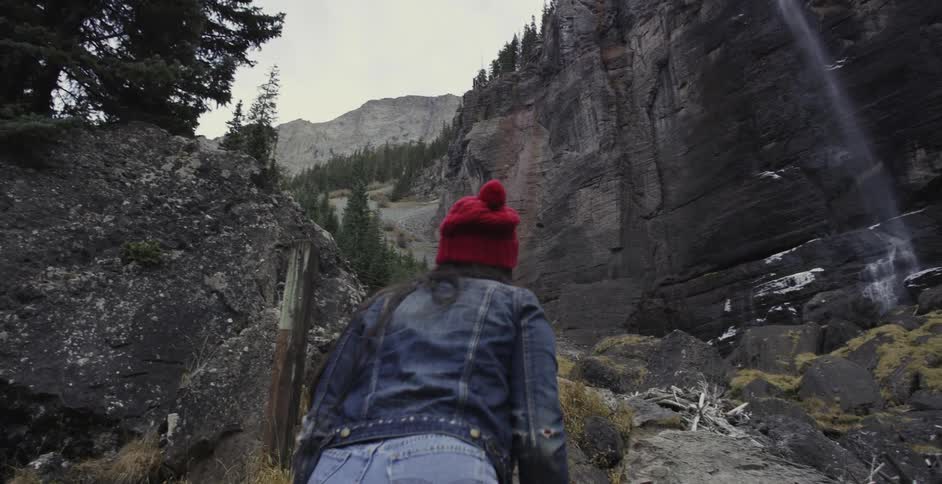 Two people observing a waterfall in the wilderness