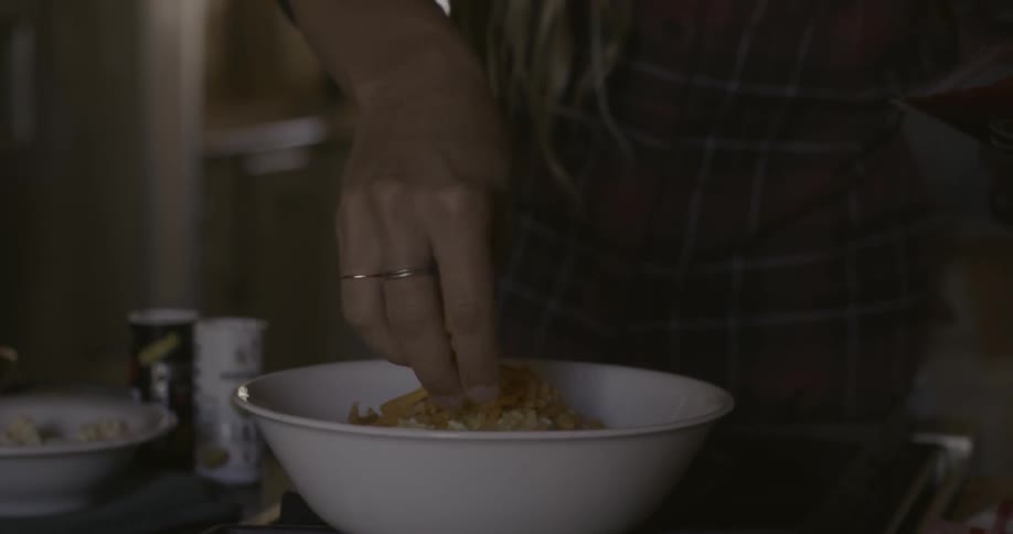 A woman sprinkles cheese over a bowl of food