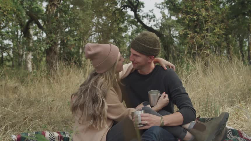 Romantic couple sitting on grass with trees in background