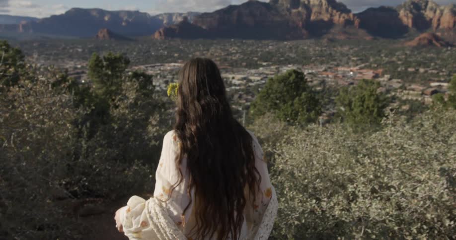Long-haired woman walking down a wilderness hillside