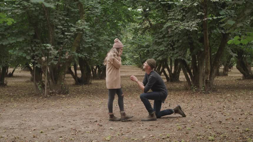Man proposes outdoors near a grove of trees then hugs his new fiance