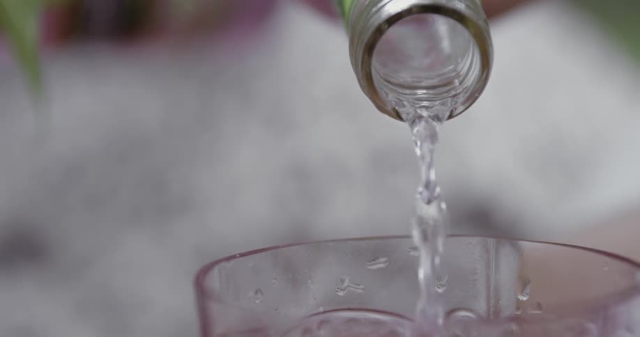 Glass cup being filled with a clear beverage