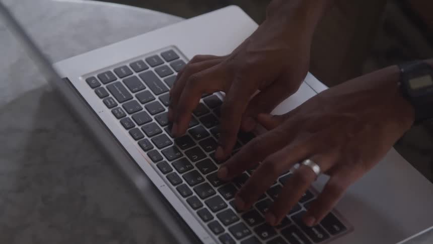 Two hands are typing on the keyboard of a laptop computer
