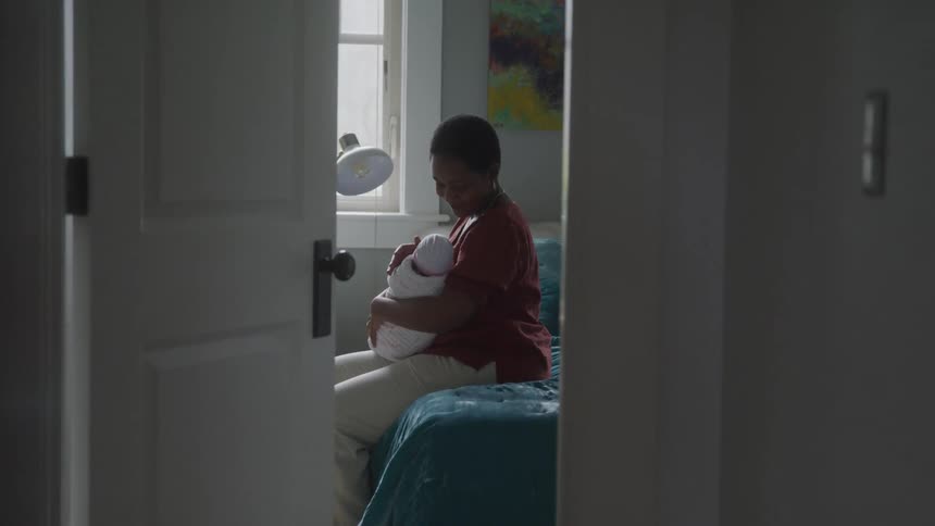 Mother sitting on bed holding baby in her lap