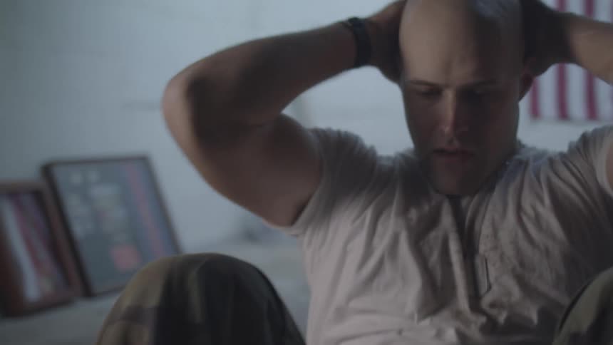 A man with no hair is doing situps