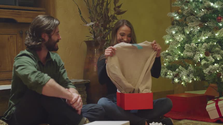 Wife happily opening christmas gift from husband and hugging him