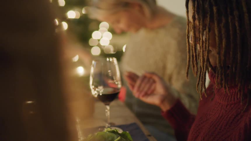 People praying and holding hands while sitting at a table before dinner