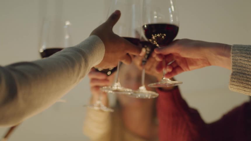 Close up of peoples hands toasting with glasses of red wine
