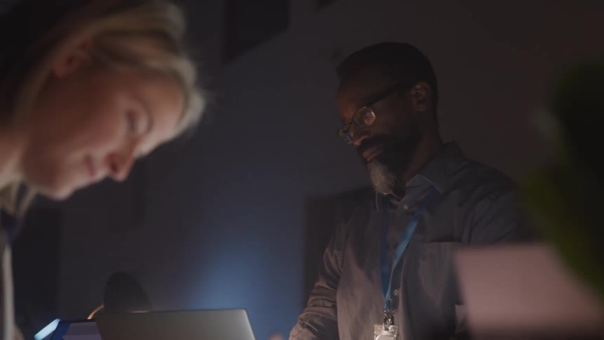 Man and a woman at an office desk working in a dimly lit room