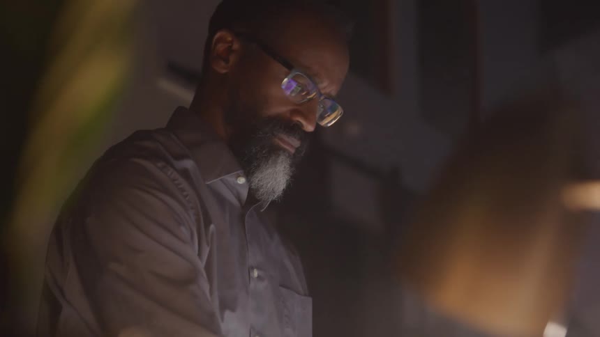 A man working on a dimly lit office focused on a task