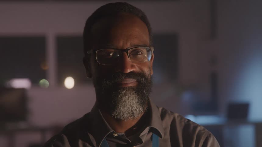 A man is smiling in the dark room