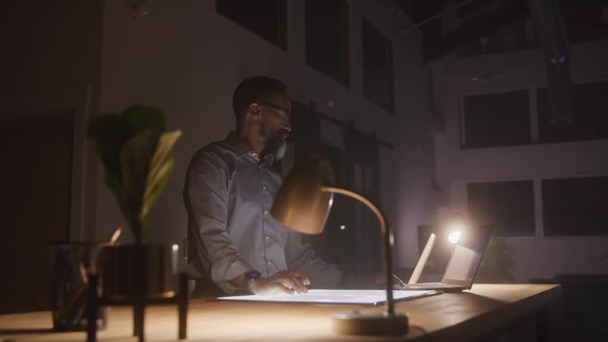 A man is using a tablet and a laptop at work