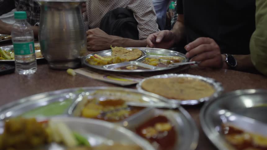A scene of people enjoying food on metal plates and a water bottle visible in the background