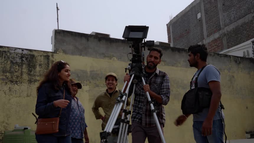 A film crew on location seemingly preparing for or reviewing a shot