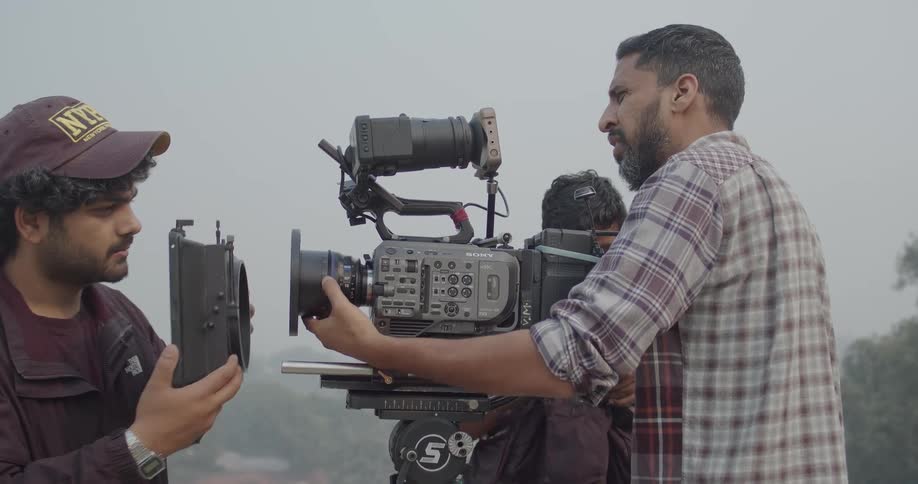 A film crew focused on adjusting the lens of a camera outdoors