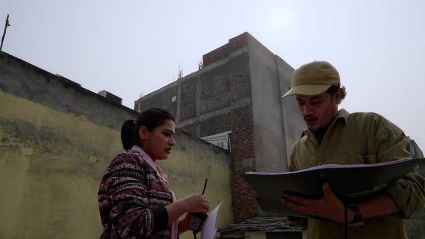 Man and woman directors on a terrace talking and taking notes in a notebook