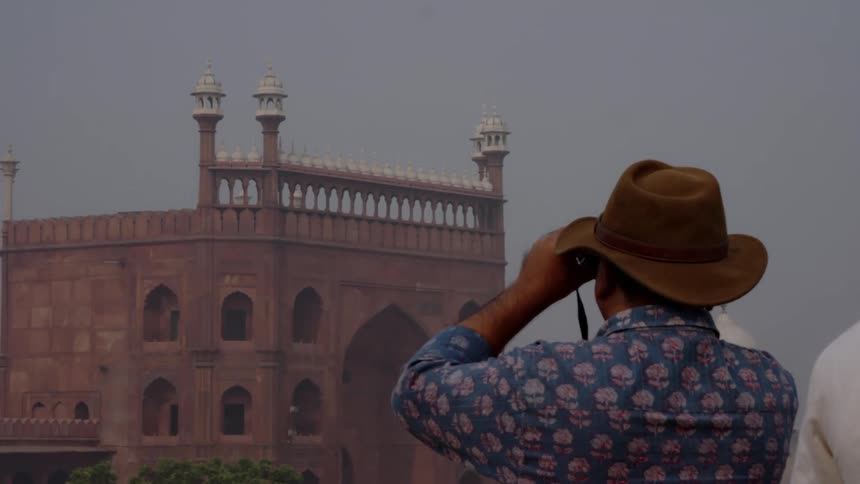 Man with hat observing a large architectural structure