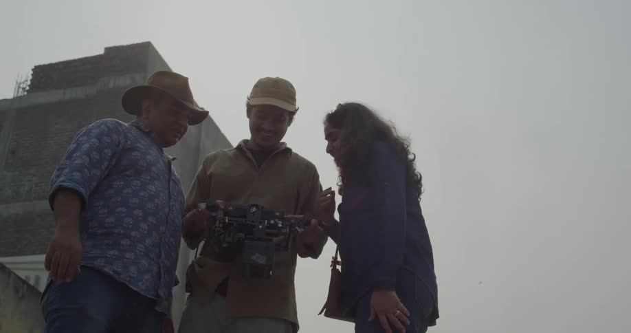 A film crew is shooting a scene outdoors on a cloudy day