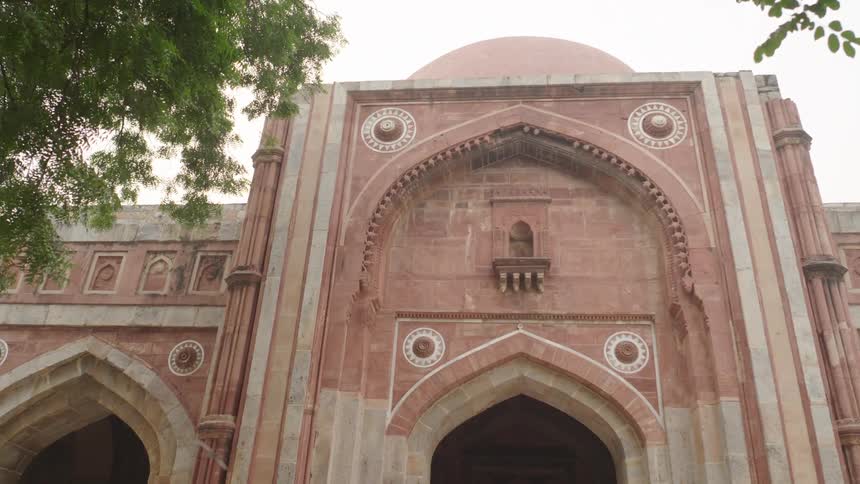 A bird flies across the face of a mosque