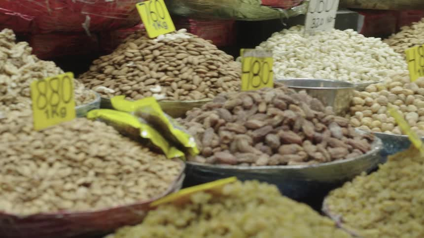 Person doing math on a calculator while standing next to bulk grains sold at a market