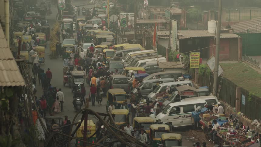 People and vehicles fill the road on a smoggy day