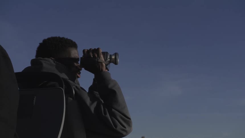 Man outdoors filming with a camera